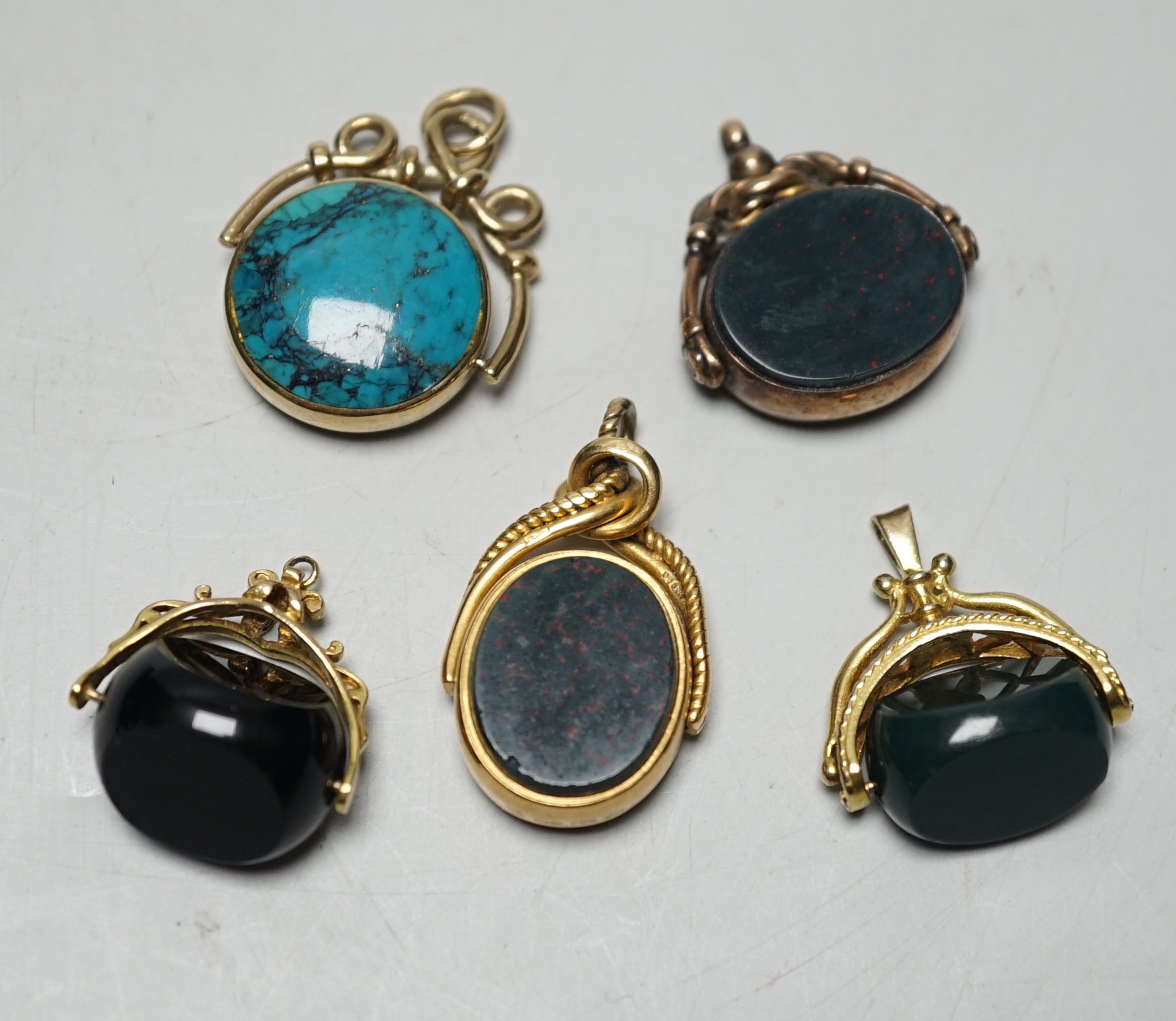 A late Victorian 18ct gold mounted bloodstone and carnelian set spinning fob seal, 36mm, a similar 9ct seal, a yellow metal and turquoise set fob seal and two later 9ct gold mounted seals.